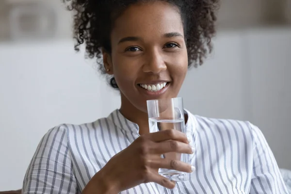 Glückliche Afrikanerin hält Glas mit frischem, reinem Wasser in der Hand. — Stockfoto