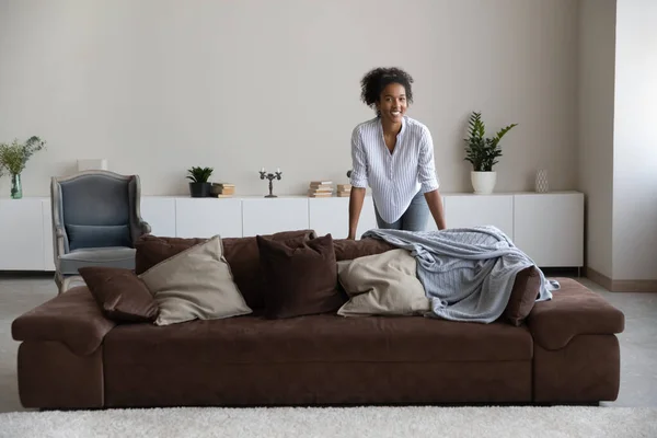 Vreugdevolle duizendjarige Afrikaanse vrouw poseren in moderne stijlvolle woonkamer. — Stockfoto