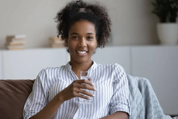 Portrait de jeune femme africaine souriante tenant un verre d'eau. — Photo