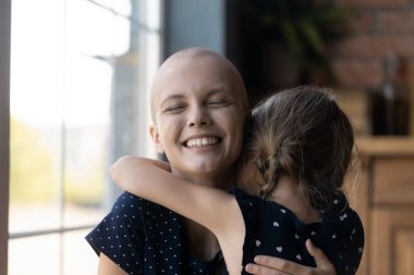 Kanserli genç bir anne, kanserli bir kıza sarılıyor.