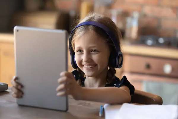 Happy little school meisje in hoofdtelefoon met behulp van online app — Stockfoto