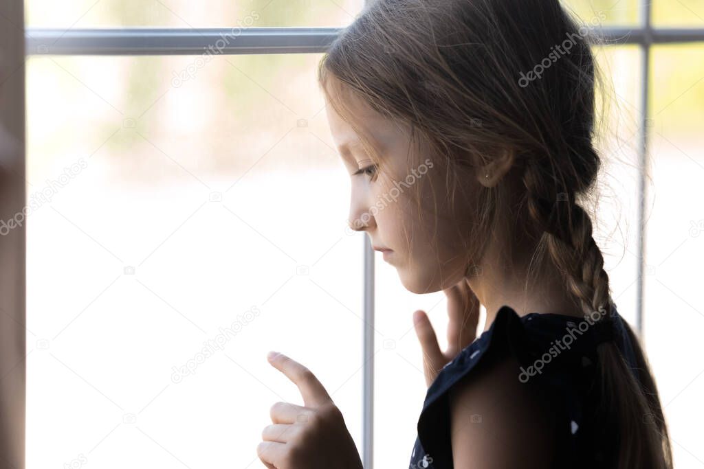 Depressed orphan kid looking out window, feeling lonely