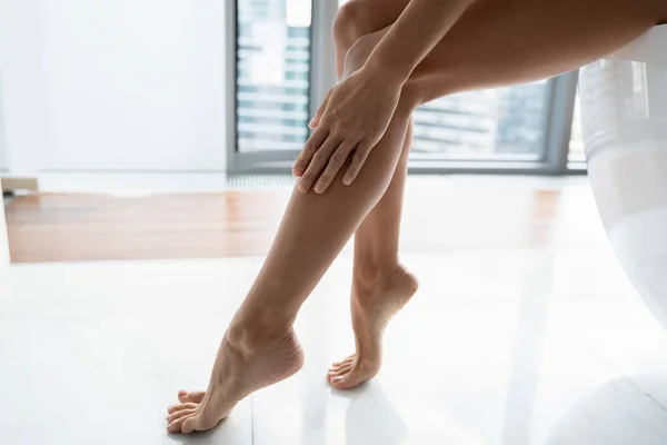 Main, cheville, pied de femme touchant la peau lisse des jambes sans poils — Photo