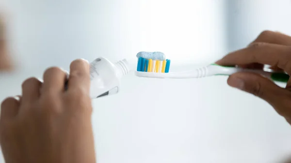 Hands of woman cleaning teeth, squeezing whitening paste