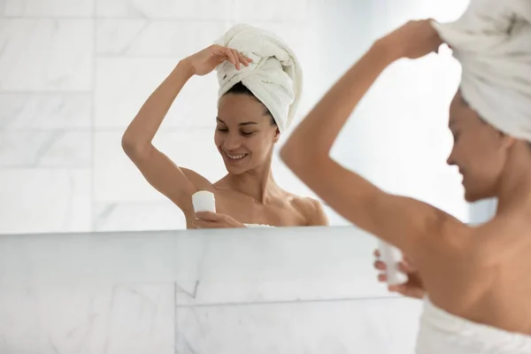 Happy woman wrapped in towels using deodorant — Stock Photo, Image