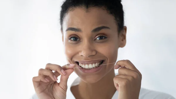 Happy cute African American girl flossing white teeth — Stock Photo, Image