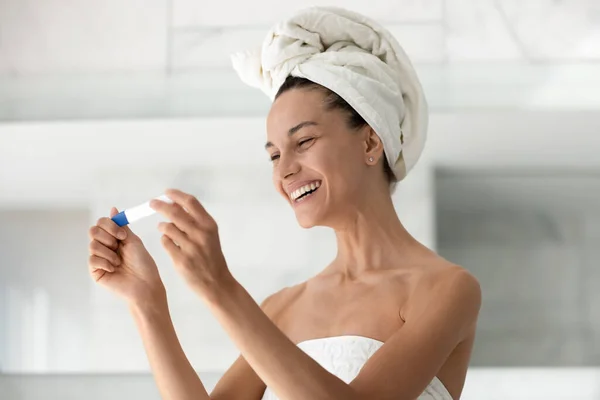 Happy excited millennial girl looking at pregnancy tester and laughing — Stock Photo, Image