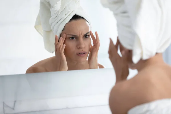 お風呂の後に鏡で顔を見て心配している女の子 — ストック写真