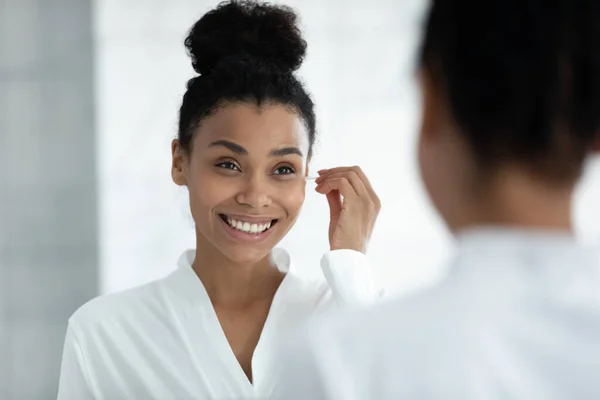 Happy girl in bathrobe cleaning ears with cotton swab — Stock Photo, Image