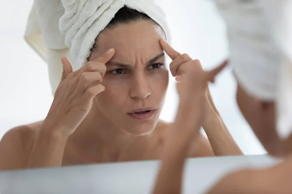 Ustaraná mladá žena zabalená v ručníku při pohledu do zrcadla — Stock fotografie