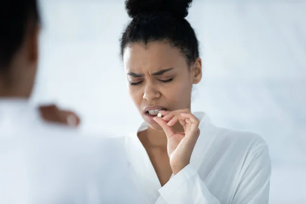 Stressed upset young Black woman with painful grimace taking meds — Stock Photo, Image