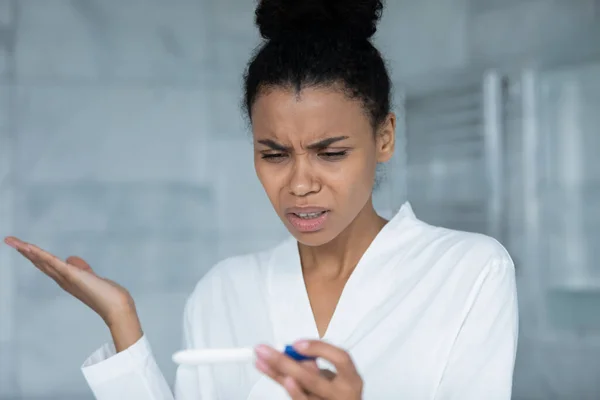 Zaskoczona czarna kobieta ma wątpliwości co do wyniku testu ciążowego — Zdjęcie stockowe