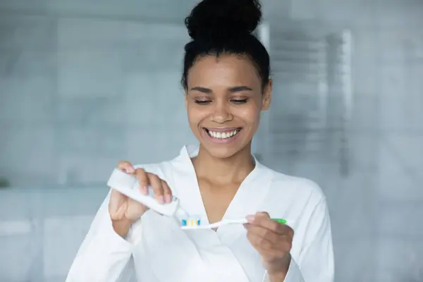 Happy young African American woman squeezing mint toothpaste — Stock Photo, Image
