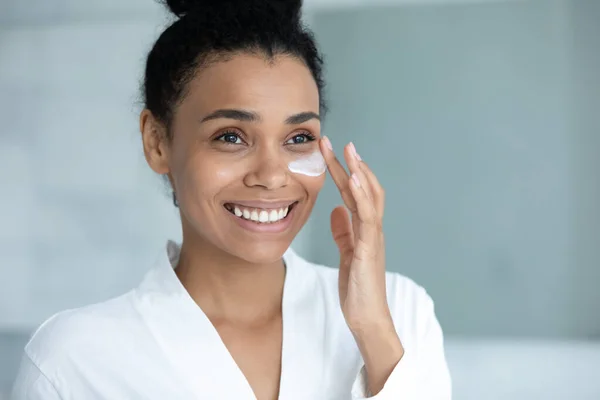Sonriente mujer afroamericana en albornoz difusión crema hidratante de colágeno —  Fotos de Stock