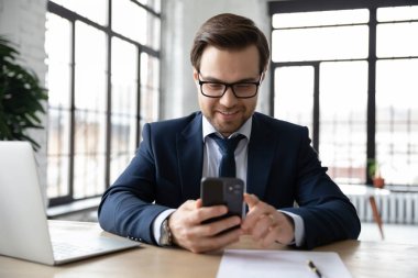 İş yerindeki akıllı telefonlarda internet uygulaması kullanan mutlu iş adamı