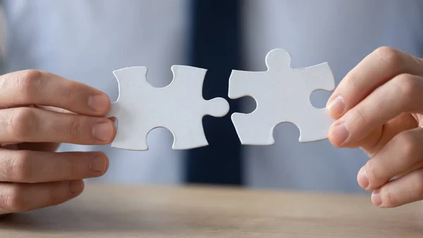 Hands of businessman connecting two pieces of puzzle