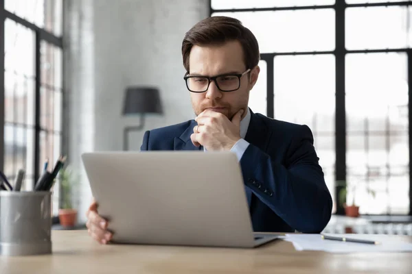 Przemyślany poważny biznesmen czytanie wiadomości e-mail na ekranie laptopa — Zdjęcie stockowe