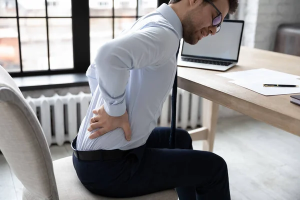 Chateado jovem funcionário do escritório que sofre de dor crônica nas costas — Fotografia de Stock