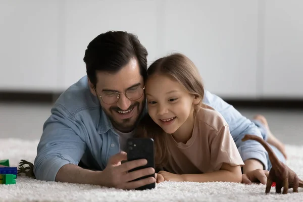 Щасливий молодий тато і маленька дочка використовують смартфон — стокове фото