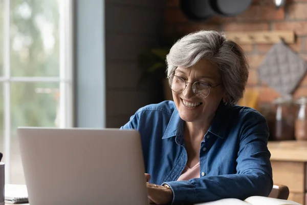 Věk žena úsměv pohled na notebook obrazovka vedení online komunikace — Stock fotografie