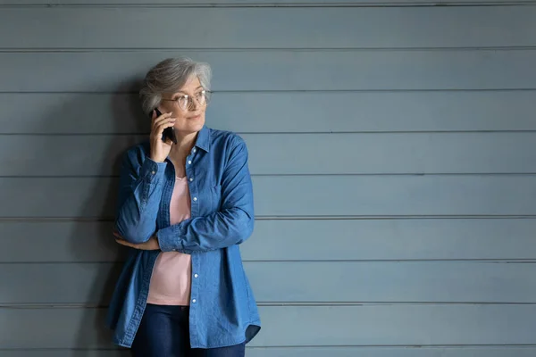 Donna matura tenendo smartphone all'orecchio guardando in lontananza — Foto Stock