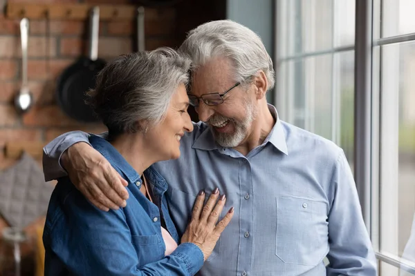 Vrolijk volwassen paar in liefde knuffelen staande indoor — Stockfoto