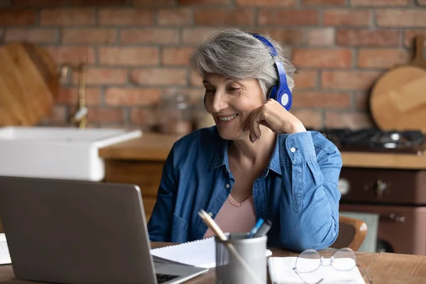 Mujer mayor en auriculares participan en conversación de videollamada —  Fotos de Stock