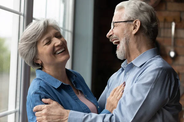 Mediana edad sin problemas pareja abrazando riendo mientras está de pie en el interior — Foto de Stock