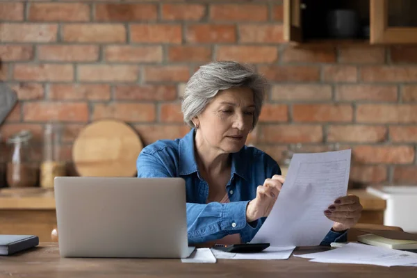 Middle-aged woman holding document checking bank statement — Stock Photo, Image