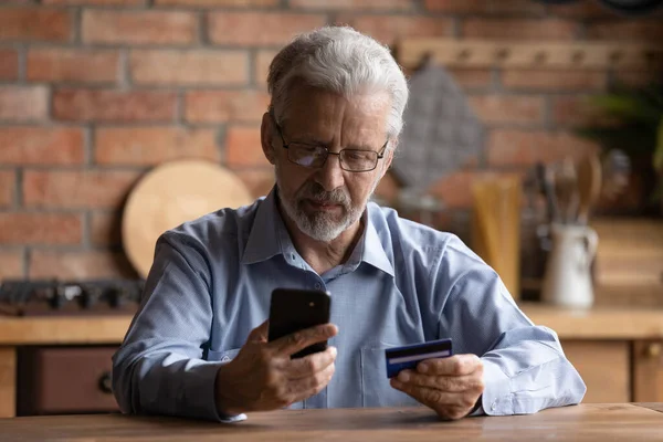 Yetişkin adam internet üzerinden kredi kartı ve akıllı telefon kullanarak alışveriş yapıyor. — Stok fotoğraf