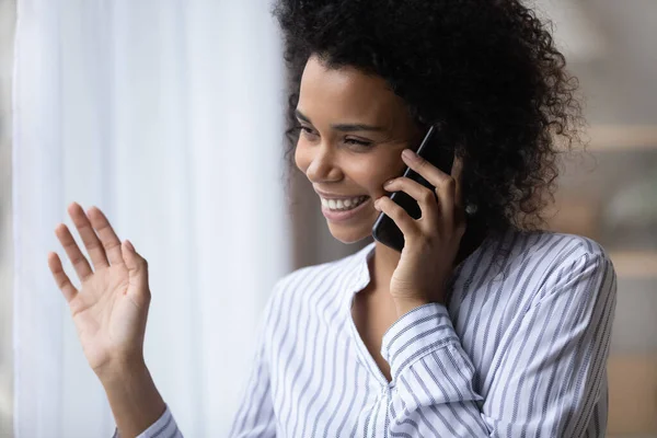 Happy biracial woman talk on smartphone look in window — Stock Photo, Image