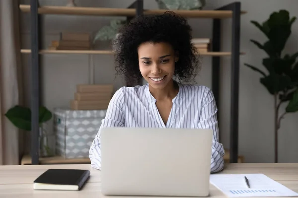 Sourire femme biraciale travailler en ligne sur ordinateur portable au bureau à la maison — Photo