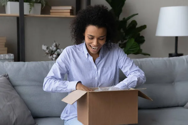 Szczęśliwy Afroamerykanka rozpakować pudełko zakupy online — Zdjęcie stockowe