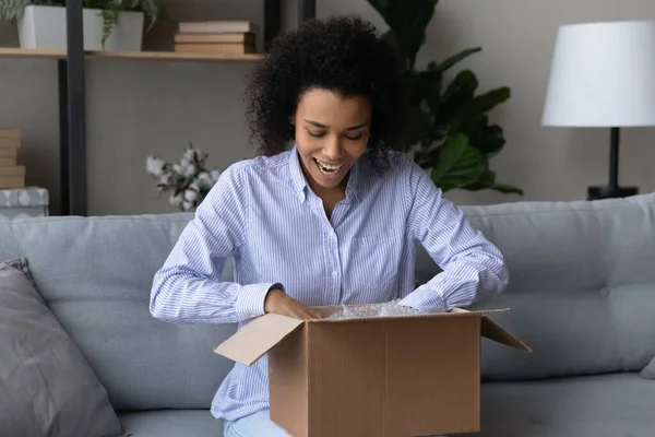 Mujer afroamericana feliz desempaquetar caja de compras en línea —  Fotos de Stock