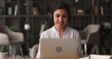 Hintli kadın kulaklık takıyor. Video çağrısı kullanarak müşteriyle uzaktan konuşuyor.