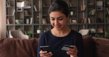 Hintli etnik kadının elinde akıllı telefon ve kredi kartı alımı var.