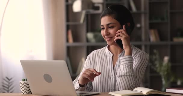 Mujer india hablar por teléfono mientras se sienta en el escritorio — Vídeo de stock