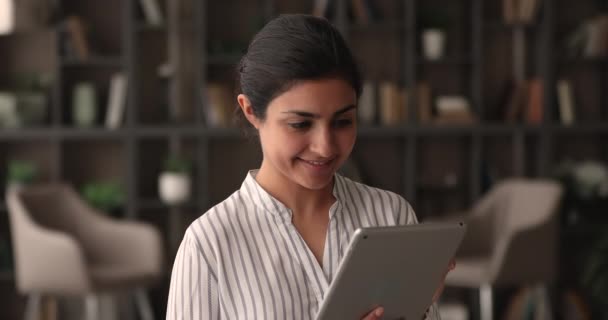 Aantrekkelijke Indiase vrouw houden tablet terwijl staan in de moderne kamer — Stockvideo