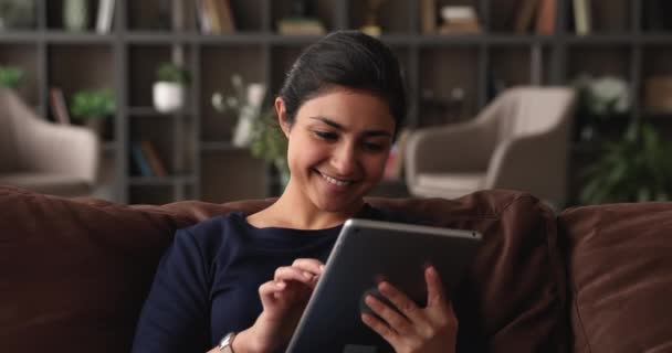 인도 여성 이 응용 프로그램을 사용하여 태블릿 장치를 들고 소파에 앉아 — 비디오