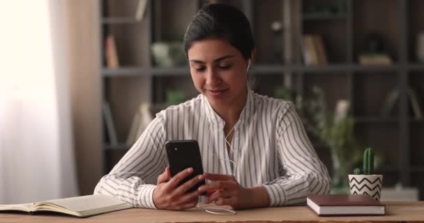 Indiase vrouw dragen bedraad koptelefoon houdt smartphone gesprekken door videoconferentie — Stockvideo