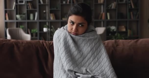 Mujer india sentarse en el sofá sensación de frío cubierto de cuadros — Vídeos de Stock