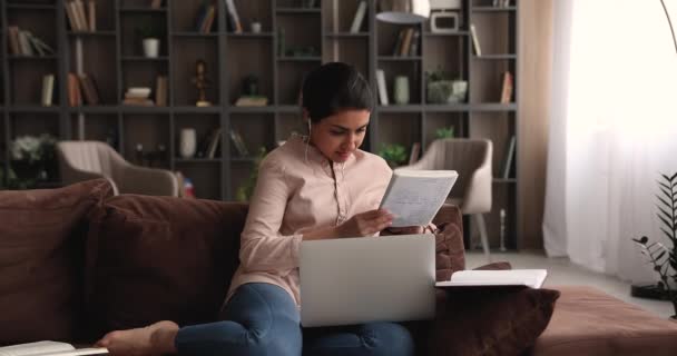 Indischer Student macht Auftrag, während er auf Sofa mit Laptop sitzt — Stockvideo