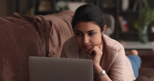 Brooding Indian wanita muda berbaring di sofa bekerja pada laptop — Stok Video