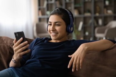 Kulaklık takan kaygısız Hintli kadın hücreden müzik dinliyor.