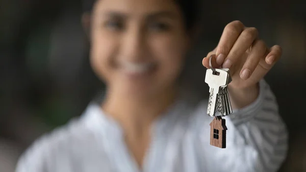 Blurred portrait of young female realtor holding key in hand