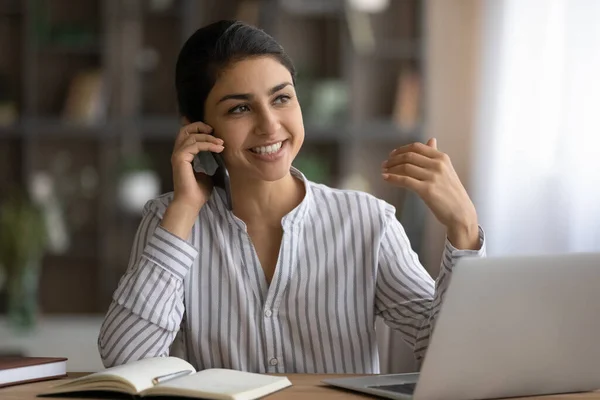 Indian woman employee make call from workplace distracted from pc — Stock Photo, Image