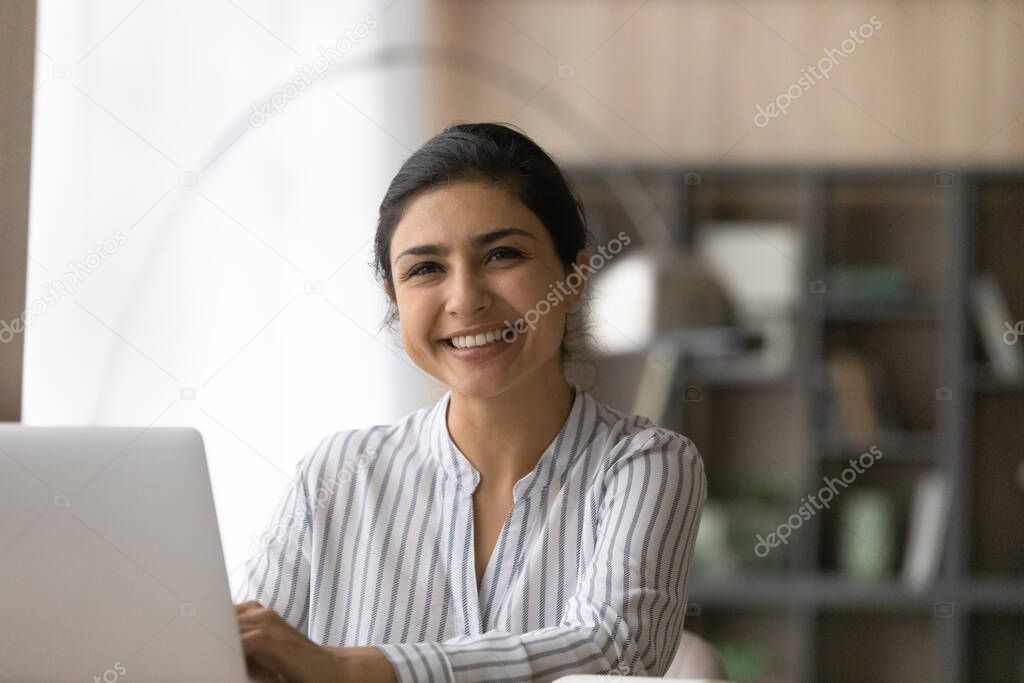 Portrait of cheerful ethnic woman using pc in office work