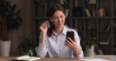 Kablosuz kulaklık takan bir kadın akıllı telefon kullanarak video konferansına başlıyor.