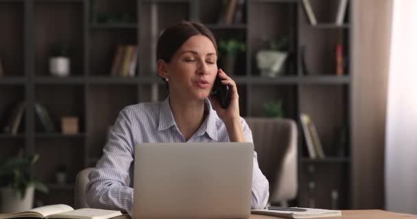 Podnikatelka mluví po telefonu, sedící u stolu na pracovišti — Stock video