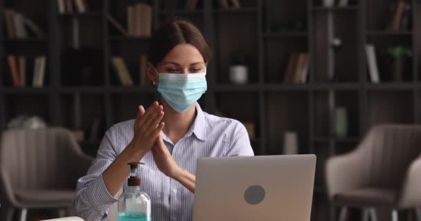 La mujer que limpia manos usa desinfectante trabajando en la oficina con mascarilla facial — Vídeo de stock